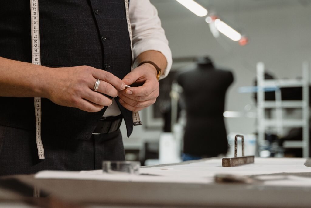 Close-up of a tailor using chalk and tape measure in a clothing atelier.